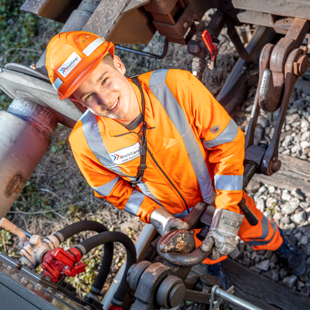 Foto eines RheinCargo Mitarbeiters in Signalweste und Schutzhelm bei der Arbeit an einer Lok